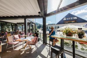 dos mujeres sentadas en mesas en un patio en Gasthof Berghof, en Semmering