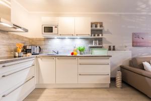 a kitchen with white cabinets and a couch at Whg 02 - MeerFreude in Zingst