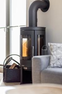 a wood stove with a couch in a living room at Ferienhof Büdlfarm - Wohlfühlhütte - 51650 in Sahrensdorf