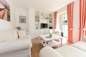 ein Wohnzimmer mit weißen Möbeln und einem Tisch in der Unterkunft Haus Stine Andresen in Wyk auf Föhr
