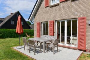 eine Terrasse mit einem Tisch, Stühlen und einem Sonnenschirm in der Unterkunft Haus Stine Andresen in Wyk auf Föhr