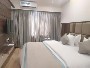 a bedroom with a large white bed and a television at Hotel Shiv Sangram in Ahmadnagar