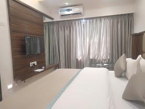 a bedroom with a large white bed and a television at Hotel Shiv Sangram in Ahmadnagar