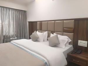 a bedroom with a large bed with white pillows at Hotel Shiv Sangram in Ahmadnagar