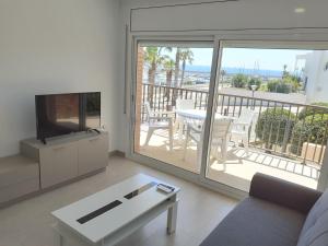 a living room with a television and a balcony at Apartamentos Dins Mar Apto. 6 in Torredembarra