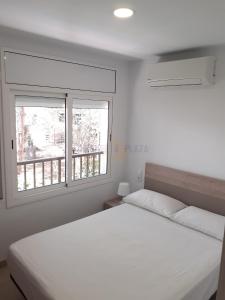 a bedroom with a white bed and two windows at Apartamentos Dins Mar Apto. 6 in Torredembarra
