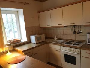 a kitchen with white cabinets and a stove and a microwave at "Uns Schün" Nr 2 in Fehmarn