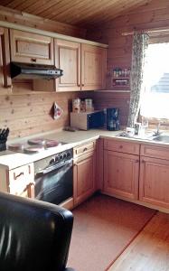 a kitchen with wooden cabinets and a stove top oven at Ferienhaus Nr 24, Typ A, Feriendorf Jägerpark, Bayerischer Wald in Viechtach