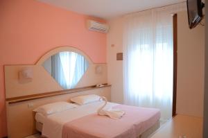 a bedroom with a bed with a mirror and a window at Hotel Gioia in San Benedetto del Tronto