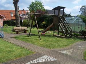 un parque infantil con un tobogán y un banco en un patio en Ferienwohnung Mauer, Wohnung "A" en Heede