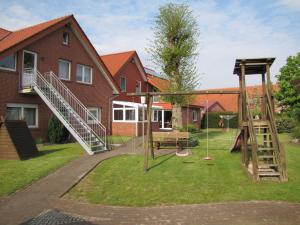 un patio con un parque infantil con un columpio en Ferienwohnung Mauer, Wohnung "A" en Heede