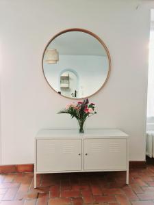 un miroir au-dessus d'une commode blanche avec un vase de fleurs dans l'établissement La maison d'Eglantine, 6 min du Puy du Fou, 4 chambres 10 couchages à St Malo-du-Bois,, à Saint-Malo-du-Bois