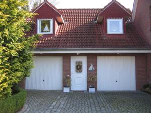 a red brick house with two white garage doors at Kinderfreundliche Ferienwohnung - Am Hufen 2 in Grömitz