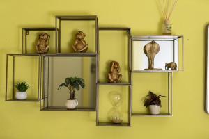 a shelf with vases and plants on a yellow wall at Noah Home in Manarola