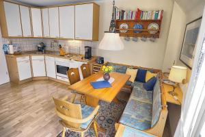 青斯特的住宿－Kranich VIII, FW 39，厨房以及带桌子和沙发的用餐室。