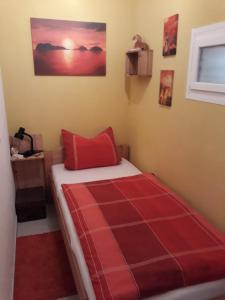 - une chambre avec un lit et une couverture rouge dans l'établissement Ferienwohnung-Zoe, à Saint-Wendel