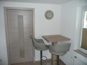 Zimmer mit einem Tisch, 2 Stühlen und einer Uhr in der Unterkunft Burkert in Grömitz
