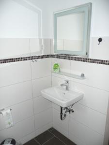 ein weißes Badezimmer mit einem Waschbecken und einem Spiegel in der Unterkunft Burkert in Grömitz