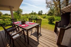 eine Holzterrasse mit einem Tisch und Stühlen darauf in der Unterkunft Typ B "Lady Nelson" -Fördehaus- in Pelzerhaken