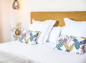 um quarto com uma cama com lençóis brancos e almofadas tropicais em Hotel Peñas Blancas em Liaño