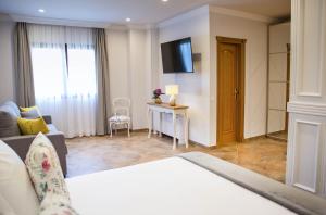 Habitación de hotel con cama, sofá y TV en Hotel Peñas Blancas en Liaño