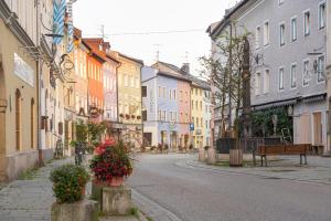an empty city street with colorful buildings and flowers at Ferienwohnung historisches Teisendorf in Teisendorf