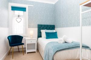 a blue and white bedroom with a bed and a chair at Red Cherry House in Watford