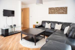 ミルトン・キーンズにあるCity Stay Apartments - Hubのリビングルーム(黒い革張りのソファ、テーブル付)