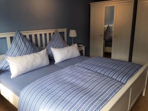 Cama grande con sábanas y almohadas azules y blancas en Stockrose en Schashagen