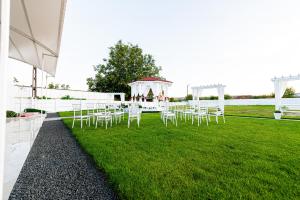 a group of white chairs on a lawn with a gazebo at Pensiunea Georgibel in Deva
