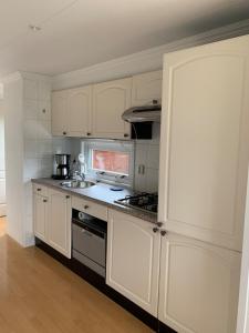 a kitchen with white cabinets and a stove top oven at Chalet Silas in Lathum