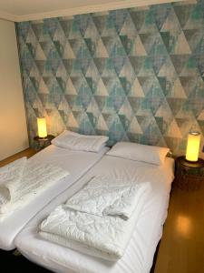 Bett in einem Zimmer mit zwei Lampen und einer Wand in der Unterkunft Chalet Silas in Lathum