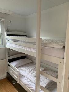 Zimmer mit 3 Etagenbetten mit weißer Bettwäsche in der Unterkunft Chalet Silas in Lathum