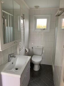 a white bathroom with a toilet and a sink at Chalet Silas in Lathum