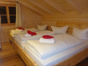 three beds in a wooden room with white sheets at Ferienwohnung Uferweg in Fischbachau