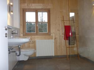 a bathroom with a toilet and a sink and a window at Ferienwohnung Uferweg in Fischbachau