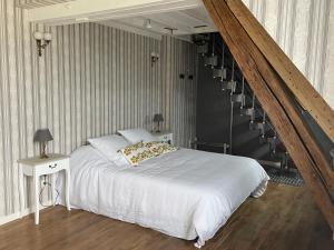 um quarto com uma cama branca e uma escada em La Métairie em Vernou-sur-Brenne