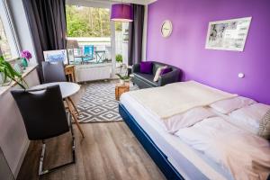 a purple bedroom with a bed and a table and a chair at Studio 11 "Blumenmeer" in Grömitz