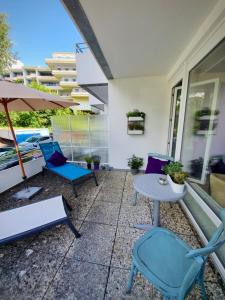 eine Terrasse mit Stühlen, einem Tisch und einem Sonnenschirm in der Unterkunft Studio 11 "Blumenmeer" in Grömitz