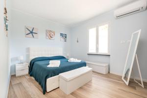 a white bedroom with a blue bed and a window at Casa Panorama, Terre Marine in Corniglia