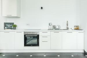 a white kitchen with white cabinets and an oven at Salty Sky Flat , Terre Marine in Corniglia