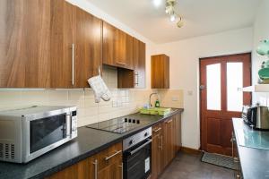 a kitchen with wooden cabinets and a microwave at The Dairy in Aberystwyth