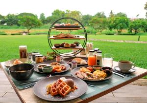 a table with plates of breakfast food on it at Cross Chiang Mai Riverside in Chiang Mai