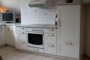 Emsland-Quartier في Bawinkel: مطبخ أبيض مع موقد وميكروويف