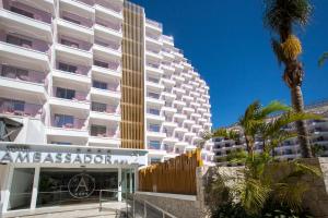 un grande edificio bianco con una palma di fronte di Ambassador Playa II a Benidorm