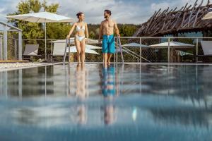 Ein Mann und eine Frau stehen neben einem Schwimmbad in der Unterkunft Seepark Wörthersee Resort in Klagenfurt am Wörthersee