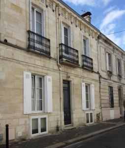 - un grand bâtiment en briques avec des fenêtres blanches et des balcons dans l'établissement Maison d'hôtes Alma, à Bordeaux