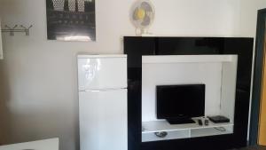 een zwart-wit entertainmentcentrum met een tv en een koelkast bij Charmante Wohnung im Stadtkern, St Wendel in Sankt Wendel