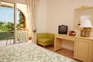 a bedroom with a bed and a desk with a television at Grand Hotel In Porto Cervo in Porto Cervo