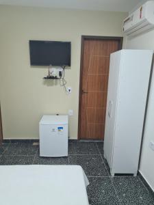 a room with a white refrigerator and a television at Suites Jangadeiro Maragogi 4 RUA JANGADEIROS 215 in Maragogi